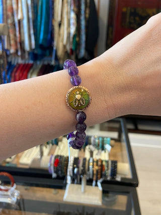 Close-up of a hand wearing an amethyst  bracelet with a store in the background