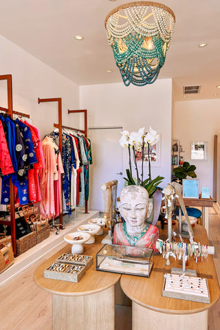Interior of a store with clothing racks, jewelry display, and Buddha statue.