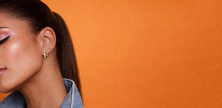 Woman wearing snake earrings against an orange background