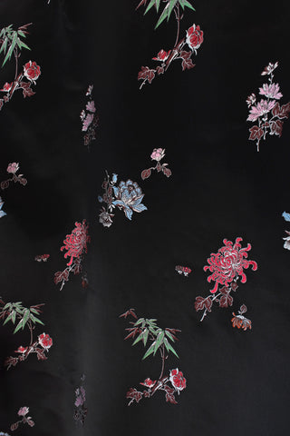 Close-up of embroidered brocade design on a dark fabric background