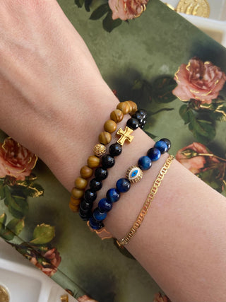 Wrist with multiple bracelets on a floral-patterned surface