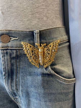 Gold and pearl butterfly brooch on a denim pants