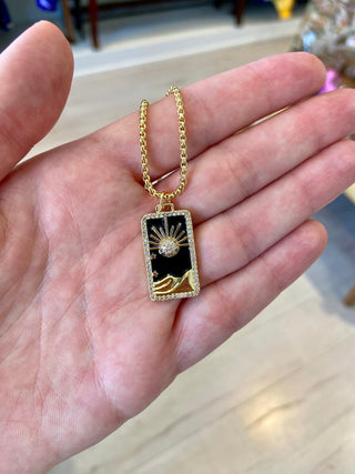 Gold necklace with a pendant held in a hand on a blurred background