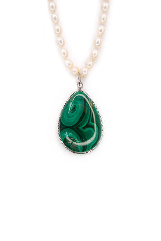 Teardrop-shaped green malachite pendant on a white pearl necklace against a white background