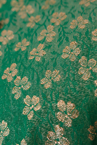 Close up of green fabric with gold clover pattern.