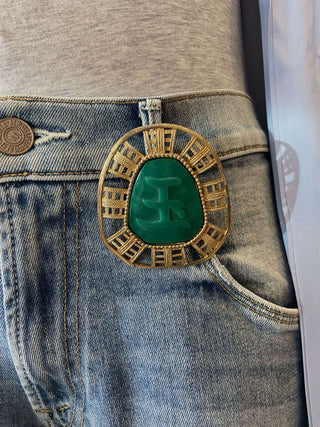 Gold and green brooch on a denim jeans