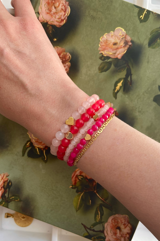 Hand wearing multiple bracelets on a floral-patterned surface