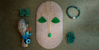 Jade jewelry set including earrings, a bracelet, and a decorative item on a textured surface.