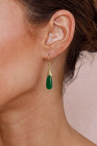 Close-up of an ear wearing a jade teardrop earring with a gold hook.