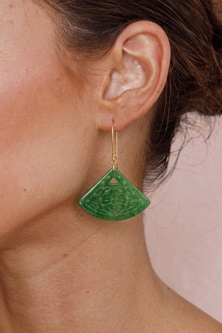 Close up of ear wearing dangling jade fan earrings.