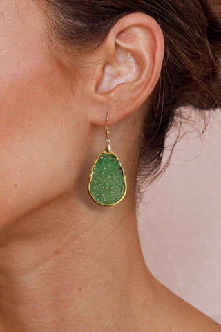 Jade earrings worn by a person on a pink background