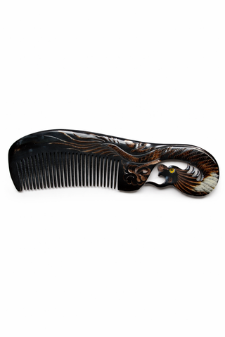 Decorative ox horn comb with intricate design on a white background