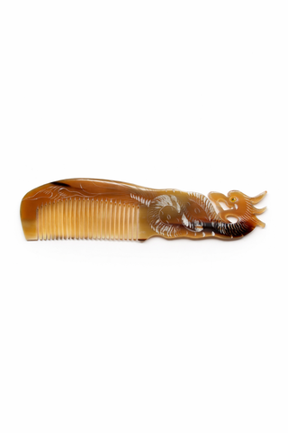 Ox horn comb comb with a dragon design on a white background