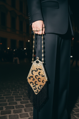 Person holding a leopard print handbag on a dark street