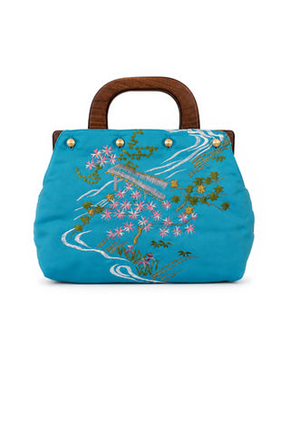 Blue handbag with floral embroidery and wooden handle on a white background