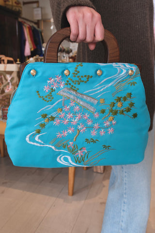 Aqua blue embroidered kimono cover back held by a hand