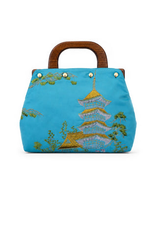 Blue handbag with embroidered design on a white background