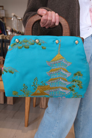 Aqua blue embroidered kimono cover back held by a hand