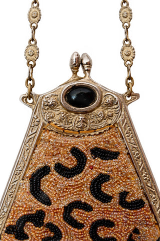 Detail of black stone on vintage handbag with beaded leopard design on a white background.