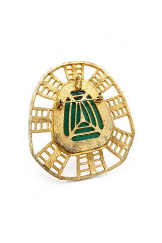 Gold and green brooch on a white background