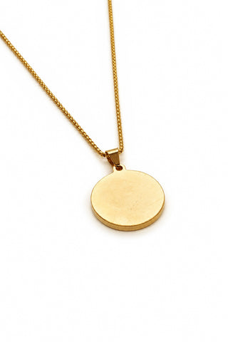 Gold necklace with a round pendant on a white background