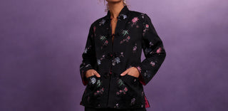 Woman wearing a black floral-patterned jacket against a purple background